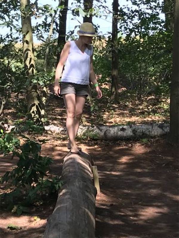 Frau balanciert über Baumstamm